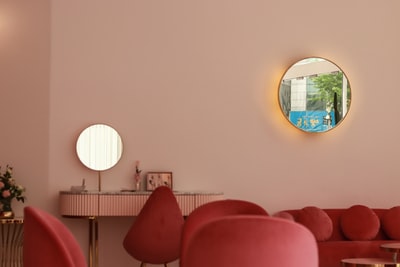 Round mirror beside the red sofa
